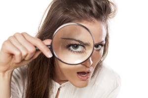 Curious woman looking through a magnifying glass.