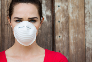 Woman wearing a mask avoiding the toxic mold in her house.