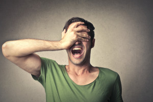 Man covering his face from anger caused by property damages repair mistakes