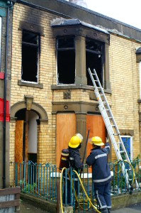 Firefighter putting out the flames from a house damaged by the fire.